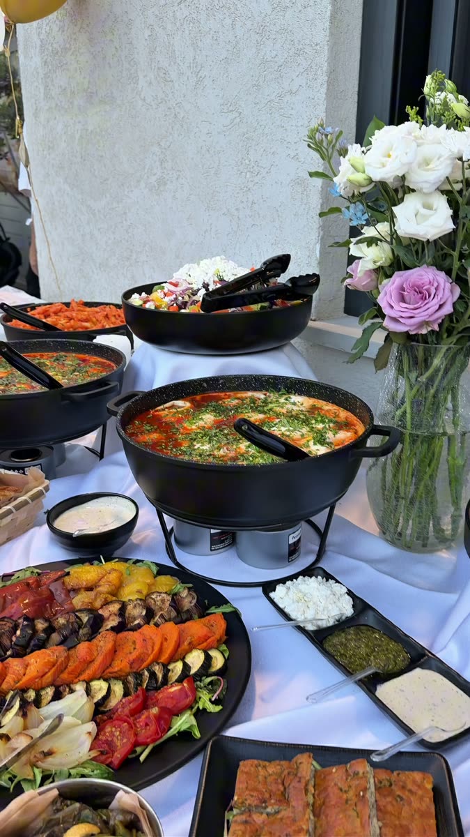 סוטאז'ים שחורים על מעמדים עם להבה, מגש ירקות צלויים ומגש רטבים מחולק